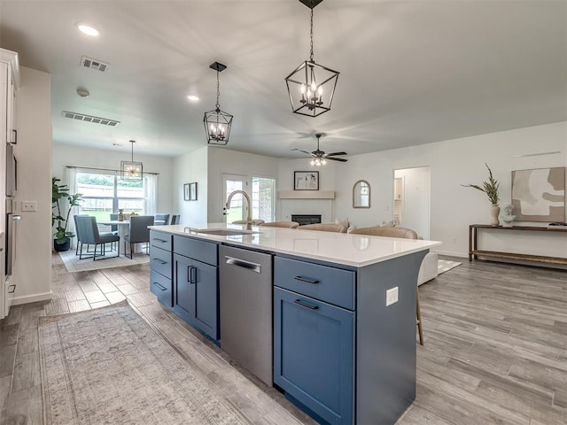 2257 Preserve Edge Dr, Edmond, OK 73034 - kitchen featuring a sink, stainless steel dishwasher, a chandelier, a ceiling fan, and a fireplace