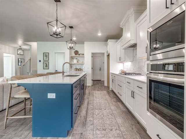 2257 Preserve Edge Dr, Edmond, OK 73034 - kitchen with a sink, appliances with stainless steel finishes, decorative backsplash, a breakfast bar, and white cabinets