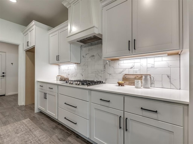 2257 Preserve Edge Dr, Edmond, OK 73034 - kitchen featuring stainless steel gas stovetop, custom range hood, white cabinets, decorative backsplash, and light countertops