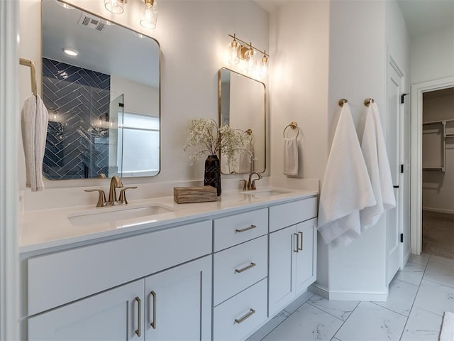 2257 Preserve Edge Dr, Edmond, OK 73034 - full bathroom with marble finish flooring, a tile shower, double vanity, baseboards, and a walk in closet