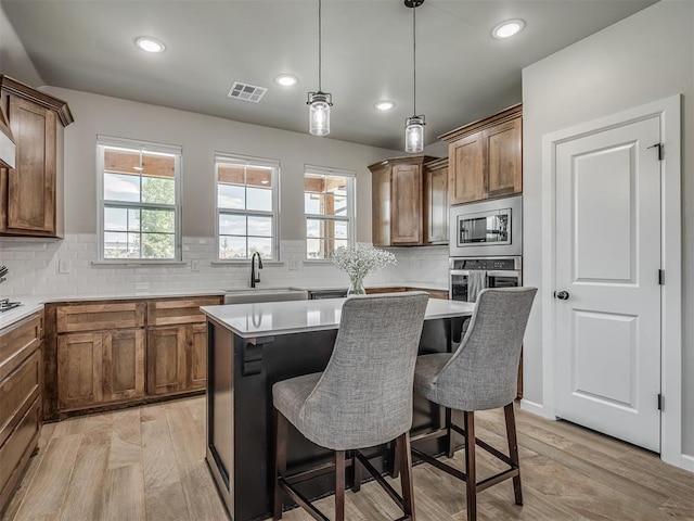 11052 NW 21st St, Yukon, OK 73099 - kitchen with stainless steel appliances, a sink, light wood-type flooring, a breakfast bar, and recessed lighting