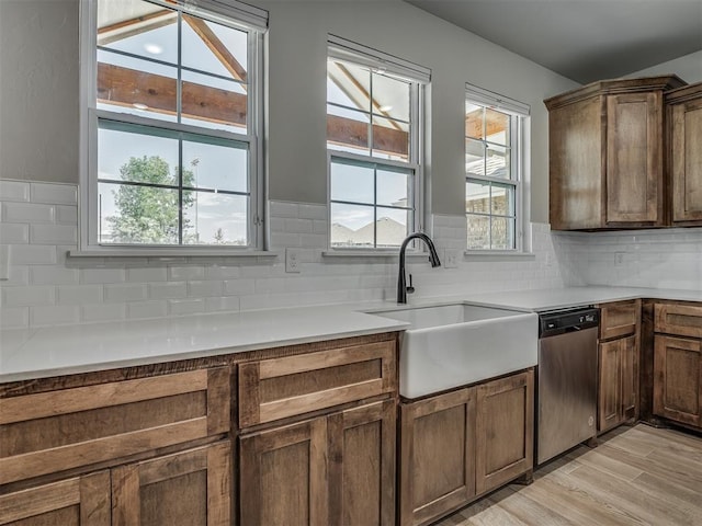 11052 NW 21st St, Yukon, OK 73099 - kitchen with stainless steel dishwasher, a sink, light wood finished floors, and tasteful backsplash