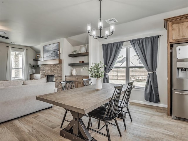 11052 NW 21st St, Yukon, OK 73099 - dining space with light wood-type flooring, a chandelier, a fireplace, baseboards, and vaulted ceiling