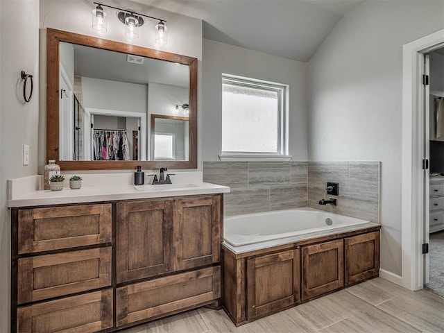 11052 NW 21st St, Yukon, OK 73099 - bathroom featuring vanity, a garden tub, a walk in closet, lofted ceiling, and wood finished floors
