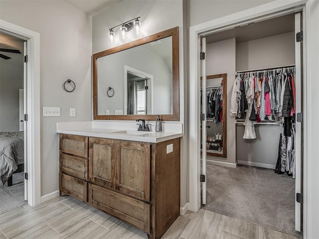 11052 NW 21st St, Yukon, OK 73099 - bathroom featuring vanity, a spacious closet, ensuite bath, baseboards, and wood finished floors