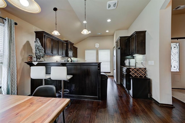 2345 NW 191st Ct, Edmond, OK 73012 - kitchen featuring dark brown cabinets, vaulted ceiling, decorative backsplash, a peninsula, and dark wood-type flooring