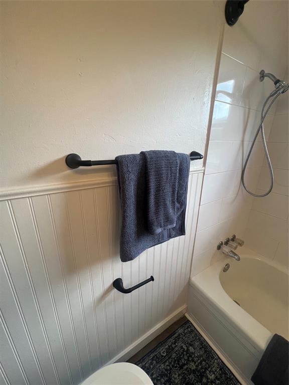 414 N 1st St, Tecumseh, OK 74873 - bathroom with washtub / shower combination, toilet, and wainscoting