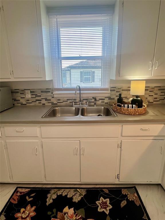 414 N 1st St, Tecumseh, OK 74873 - kitchen featuring a sink, white cabinets, and decorative backsplash