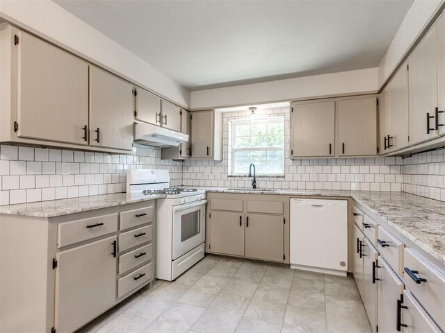 2748 Lancaster Ln, Oklahoma City, OK 73116 - kitchen featuring white appliances, a sink, under cabinet range hood, tasteful backsplash, and light stone countertops