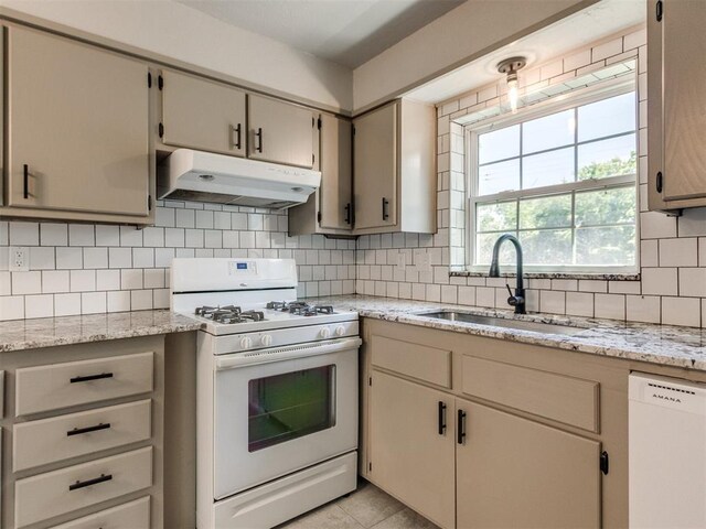 2748 Lancaster Ln, Oklahoma City, OK 73116 - kitchen with under cabinet range hood, white appliances, a sink, backsplash, and light stone countertops