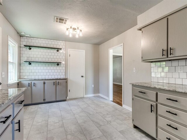2748 Lancaster Ln, Oklahoma City, OK 73116 - kitchen featuring decorative backsplash, a textured ceiling, baseboards, open shelves, and light stone counters