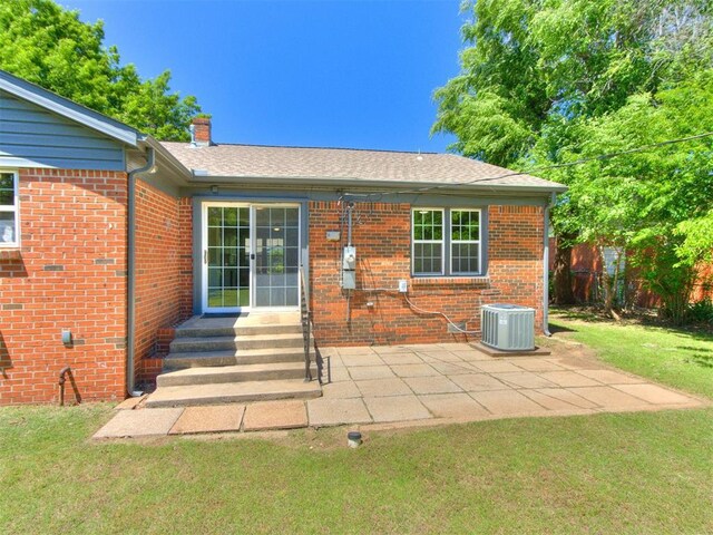 2748 Lancaster Ln, Oklahoma City, OK 73116 - back of house with central air condition unit, brick siding, a patio area, and a chimney