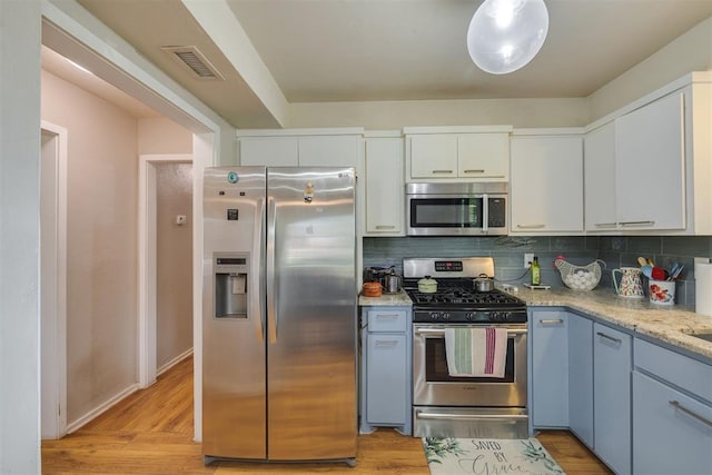 3501 Necia St, Moore, OK 73160 - kitchen with stainless steel appliances, tasteful backsplash, white cabinets, light wood finished floors, and light stone countertops