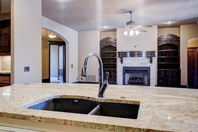 3101 Monica Ln, Moore, OK 73160 - kitchen featuring a ceiling fan, a fireplace, built in features, and light stone counters