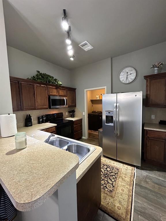 9525 SW 27th St, Oklahoma City, OK 73128 - kitchen with stainless steel appliances, a sink, light countertops, a peninsula, and dark brown cabinets