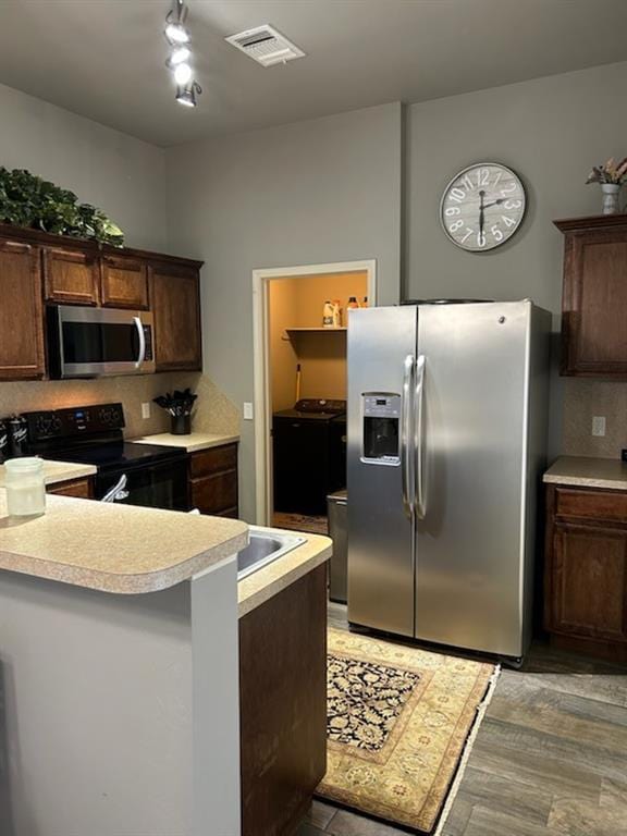 9525 SW 27th St, Oklahoma City, OK 73128 - kitchen featuring stainless steel appliances, light countertops, washer and dryer, dark brown cabinetry, and a peninsula