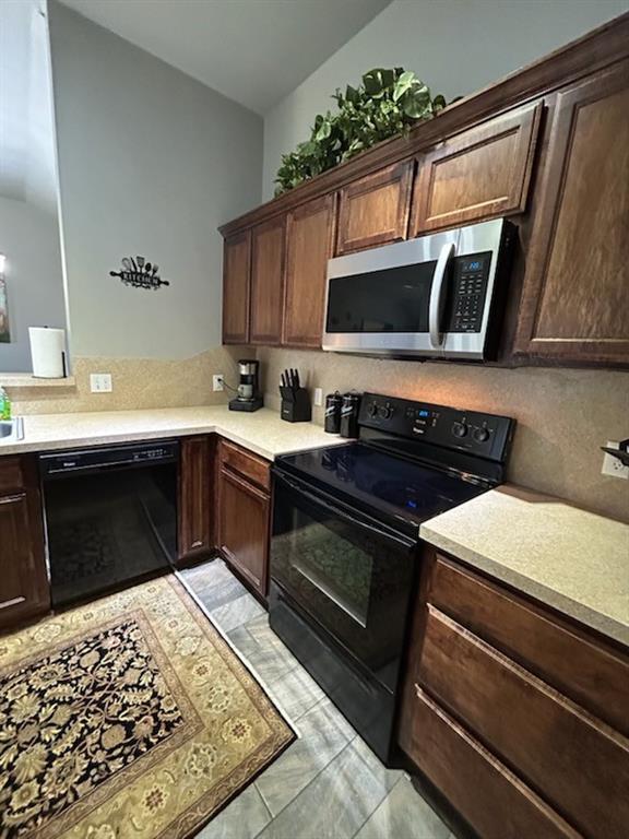 9525 SW 27th St, Oklahoma City, OK 73128 - kitchen with black appliances, light countertops, tasteful backsplash, dark brown cabinets, and vaulted ceiling