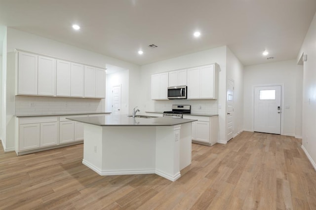2836 NW 28th St, Yukon, OK 73099 - kitchen with appliances with stainless steel finishes, tasteful backsplash, a sink, light wood-style flooring, and a center island with sink