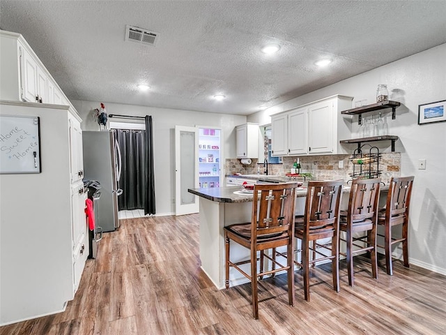 1202 N 8th Ave, Purcell, OK 73080 - kitchen with a peninsula, open shelves, light wood-style floors, a textured ceiling, and baseboards