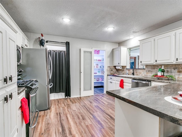 1202 N 8th Ave, Purcell, OK 73080 - kitchen with stainless steel appliances, dark countertops, a sink, light wood-style flooring, and white cabinets