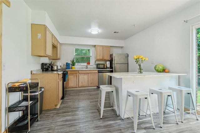 4301 NW 18th St, Oklahoma City, OK 73107 - kitchen featuring appliances with stainless steel finishes, wood finished floors, a kitchen bar, and healthy amount of natural light