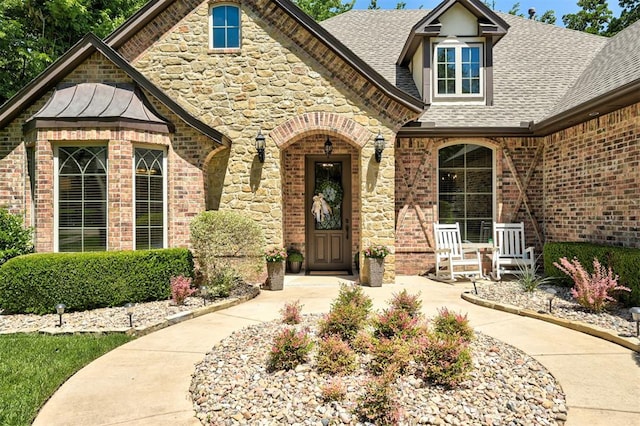 2139 Rivanna Way, Edmond, OK 73034 - entrance to property featuring a shingled roof, a porch, brick siding, and a standing seam roof