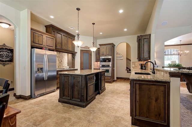 2139 Rivanna Way, Edmond, OK 73034 - kitchen with appliances with stainless steel finishes, arched walkways, light stone countertops, decorative backsplash, and dark brown cabinets