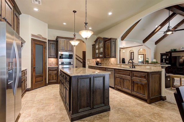 2139 Rivanna Way, Edmond, OK 73034 - kitchen with stainless steel appliances, arched walkways, decorative backsplash, recessed lighting, and dark brown cabinetry