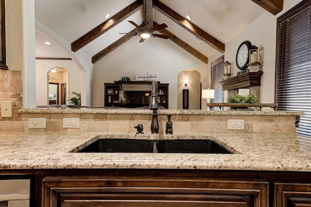 2139 Rivanna Way, Edmond, OK 73034 - kitchen with arched walkways, ceiling fan, and light stone counters
