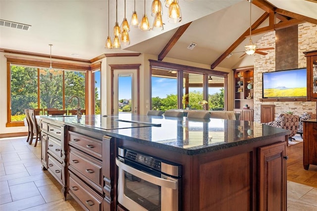 1516 Brook Bank Dr, Jones, OK 73049 - kitchen with oven, a center island with sink, dark stone countertops, beam ceiling, and a ceiling fan