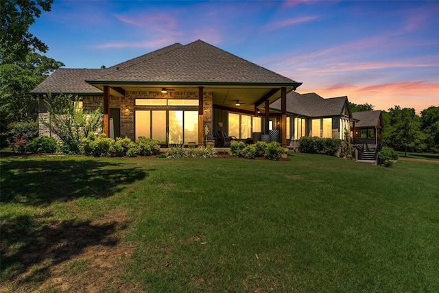 1516 Brook Bank Dr, Jones, OK 73049 - back of property at dusk with a ceiling fan, a yard, a shingled roof, and brick siding