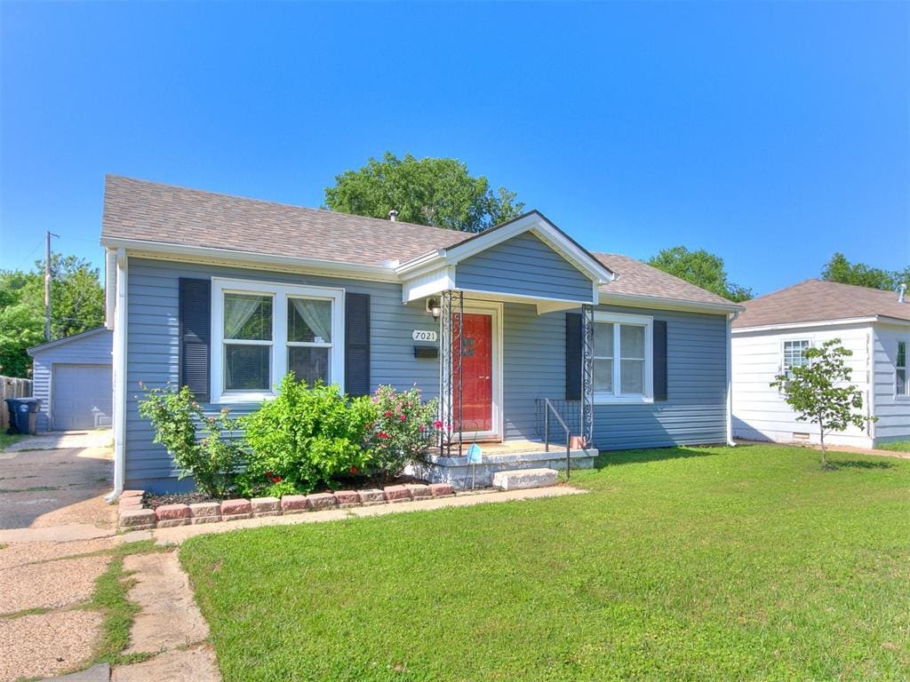 7021 NW 48th St, Bethany, OK 73008 - view of front of property featuring an outdoor structure, a front yard, a detached garage, a shingled roof, and asphalt driveway