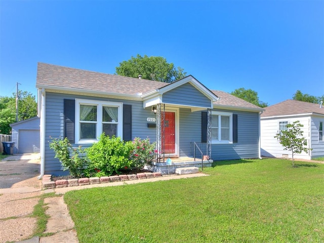 7021 NW 48th St, Bethany, OK 73008 - view of front of property featuring an outdoor structure, a front yard, a detached garage, a shingled roof, and asphalt driveway