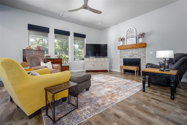 1225 N Nature Way, Mustang, OK 73064 - living area featuring ceiling fan, wood finished floors, a stone fireplace, and baseboards
