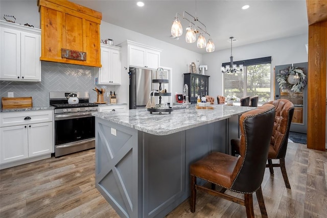 1225 N Nature Way, Mustang, OK 73064 - kitchen with stainless steel appliances, a chandelier, light stone counters, tasteful backsplash, and light wood-style flooring