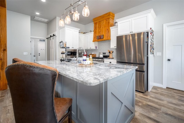 1225 N Nature Way, Mustang, OK 73064 - kitchen featuring stainless steel appliances, light stone counters, decorative backsplash, light wood-style flooring, and white cabinets