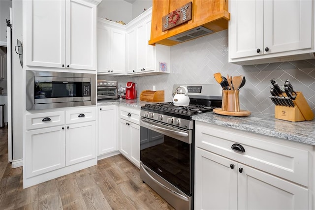 1225 N Nature Way, Mustang, OK 73064 - kitchen featuring appliances with stainless steel finishes, white cabinetry, decorative backsplash, and light wood finished floors