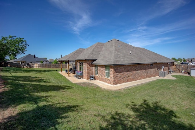 1225 N Nature Way, Mustang, OK 73064 - back of property with central AC unit, brick siding, a patio area, and roof with shingles