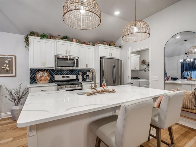 13325 SW 5th St, Yukon, OK 73099 - kitchen with appliances with stainless steel finishes, independent washer and dryer, lofted ceiling, light wood finished floors, and white cabinets