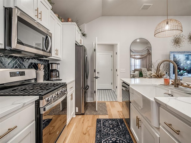 13325 SW 5th St, Yukon, OK 73099 - kitchen featuring appliances with stainless steel finishes, a sink, lofted ceiling, light wood-type flooring, and white cabinets