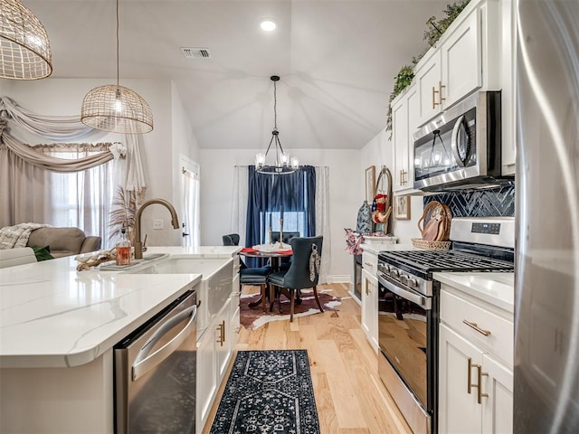 13325 SW 5th St, Yukon, OK 73099 - kitchen with stainless steel appliances, a chandelier, vaulted ceiling, white cabinets, and light stone countertops