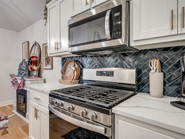 13325 SW 5th St, Yukon, OK 73099 - kitchen with appliances with stainless steel finishes, white cabinetry, decorative backsplash, and light stone counters