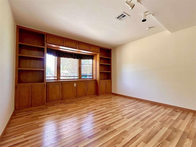 1312 N Carol Ln, Oklahoma City, OK 73127 - unfurnished room featuring light wood-style floors, built in shelves, rail lighting, and baseboards