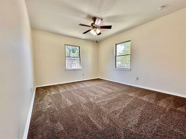 1312 N Carol Ln, Oklahoma City, OK 73127 - empty room with plenty of natural light, a ceiling fan, and dark colored carpet