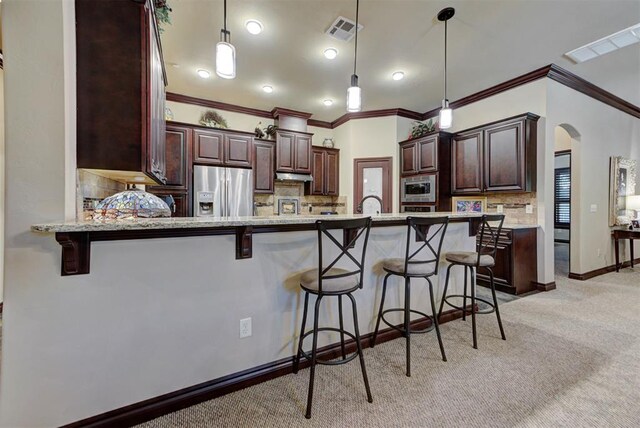 13009 Jasmine Ln, Oklahoma City, OK 73142 - kitchen featuring appliances with stainless steel finishes, light carpet, arched walkways, tasteful backsplash, and a kitchen bar