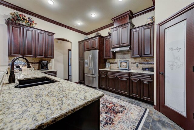 13009 Jasmine Ln, Oklahoma City, OK 73142 - kitchen featuring a sink, stainless steel refrigerator with ice dispenser, under cabinet range hood, ornamental molding, and tasteful backsplash