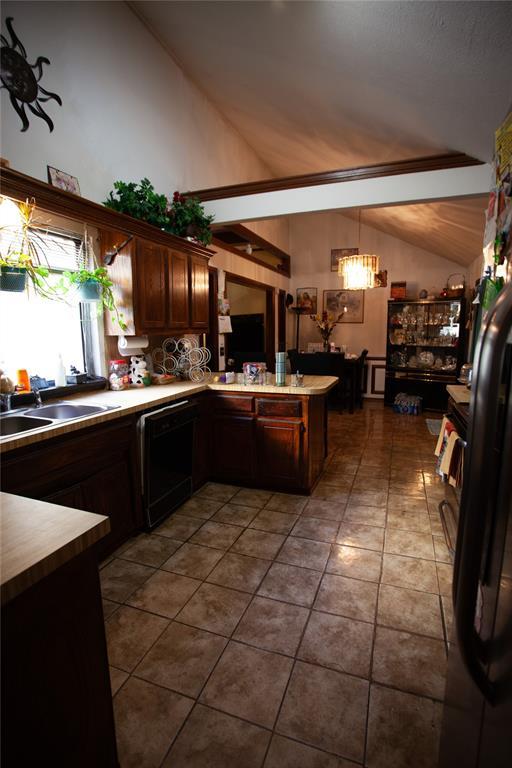 11332 Cimarron Dr, Oklahoma City, OK 73162 - kitchen featuring black dishwasher, a peninsula, a sink, dark brown cabinets, and high vaulted ceiling