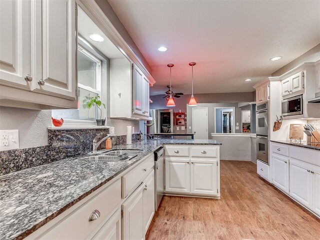 12601 Rock Springs Rd, Jones, OK 73049 - kitchen featuring a sink, stainless steel appliances, a peninsula, light wood-style floors, and white cabinetry