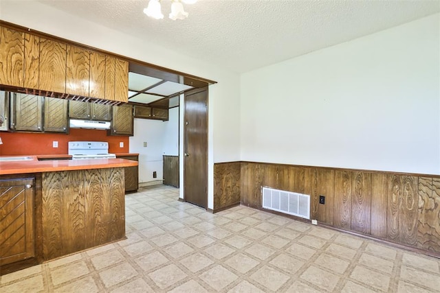 1101 S English St, Moore, OK 73160 - kitchen featuring light floors, white electric stove, a wainscoted wall, under cabinet range hood, and light countertops