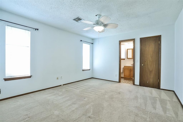 1101 S English St, Moore, OK 73160 - unfurnished bedroom featuring a textured ceiling, light colored carpet, baseboards, connected bathroom, and a ceiling fan